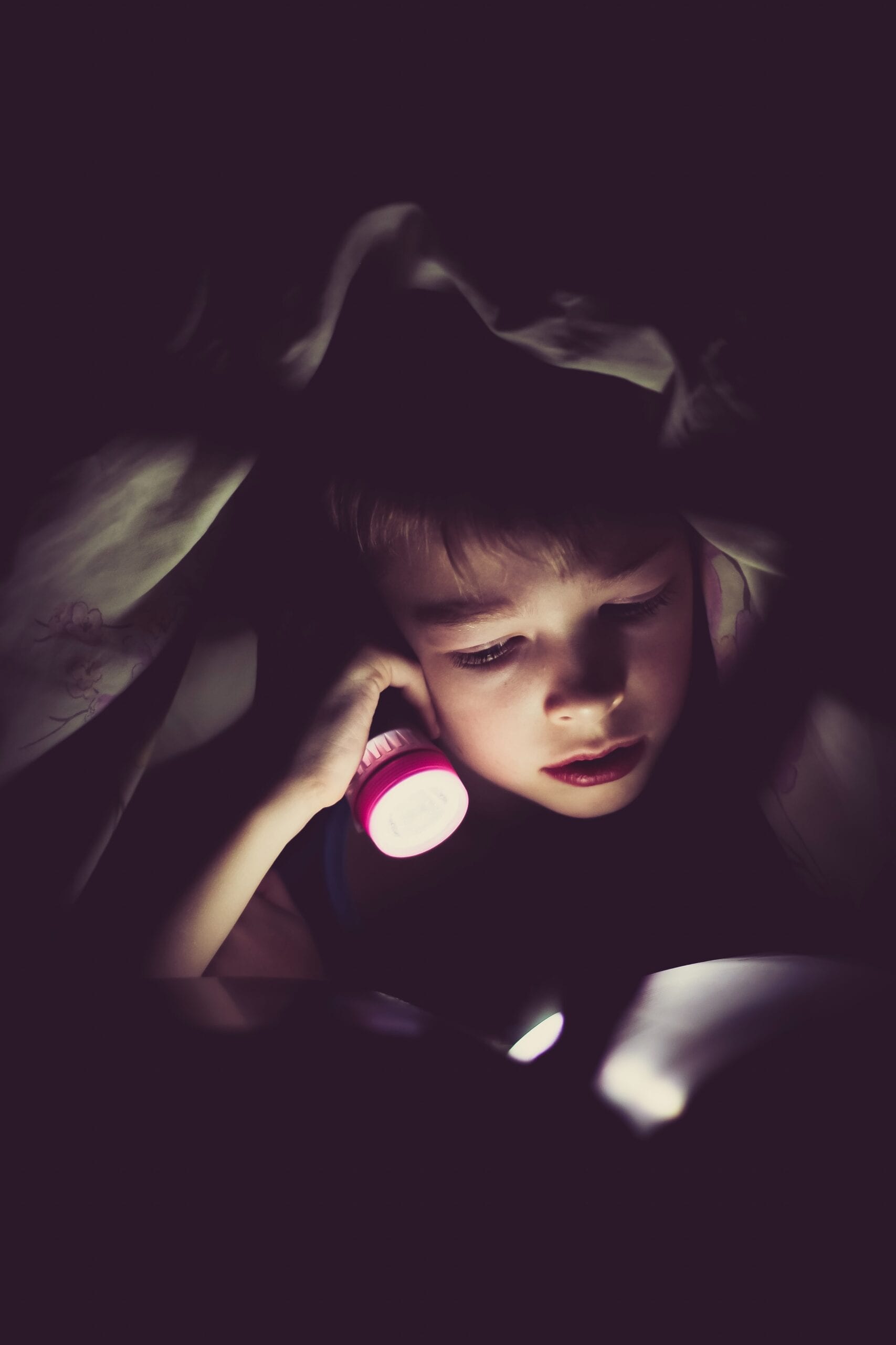 Child reading by flashlight